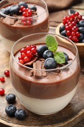Photo of Delicious panna cotta with chocolate, berries and mint on table, closeup