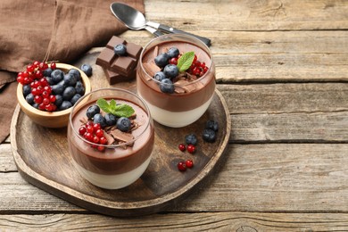 Photo of Delicious panna cotta with chocolate, berries and mint on wooden table, closeup. Space for text