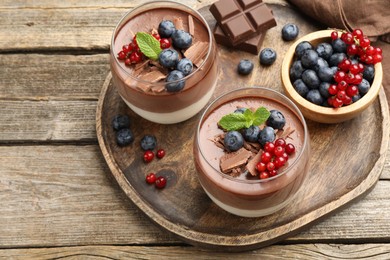 Photo of Delicious panna cotta with chocolate, berries and mint on wooden table, above view. Space for text
