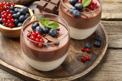Photo of Delicious panna cotta with chocolate, berries and mint on wooden table, closeup