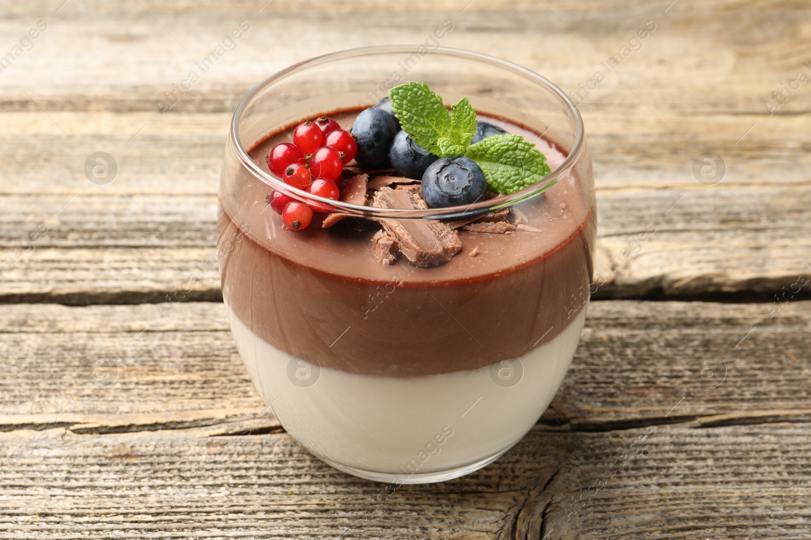 Delicious panna cotta with chocolate, berries and mint on wooden table, closeup Photo of Delicious panna cotta with chocolate, berries and mint on wooden table, closeup