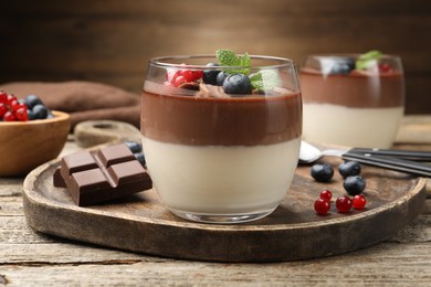 Photo of Delicious panna cotta with chocolate, berries and mint on wooden table, closeup