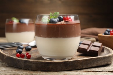 Photo of Delicious panna cotta with chocolate, berries and mint on wooden table, closeup