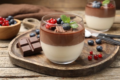 Photo of Delicious panna cotta with chocolate, berries and mint on wooden table, closeup