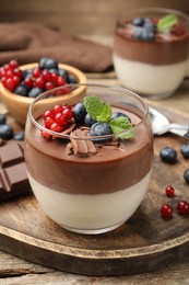 Photo of Delicious panna cotta with chocolate, berries and mint on wooden table, closeup
