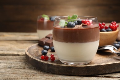 Photo of Delicious panna cotta with chocolate, berries and mint on wooden table, closeup