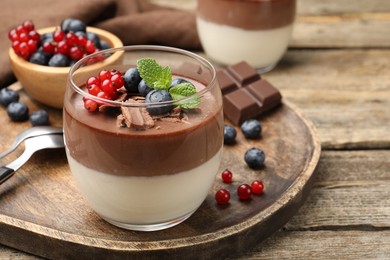 Photo of Delicious panna cotta with chocolate, berries and mint on wooden table, closeup