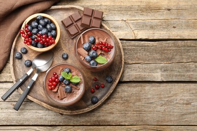 Photo of Delicious panna cotta with chocolate, berries and mint on wooden table, top view. Space for text