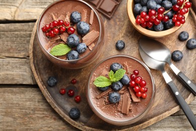 Photo of Delicious panna cotta with chocolate, berries and mint on wooden table, top view