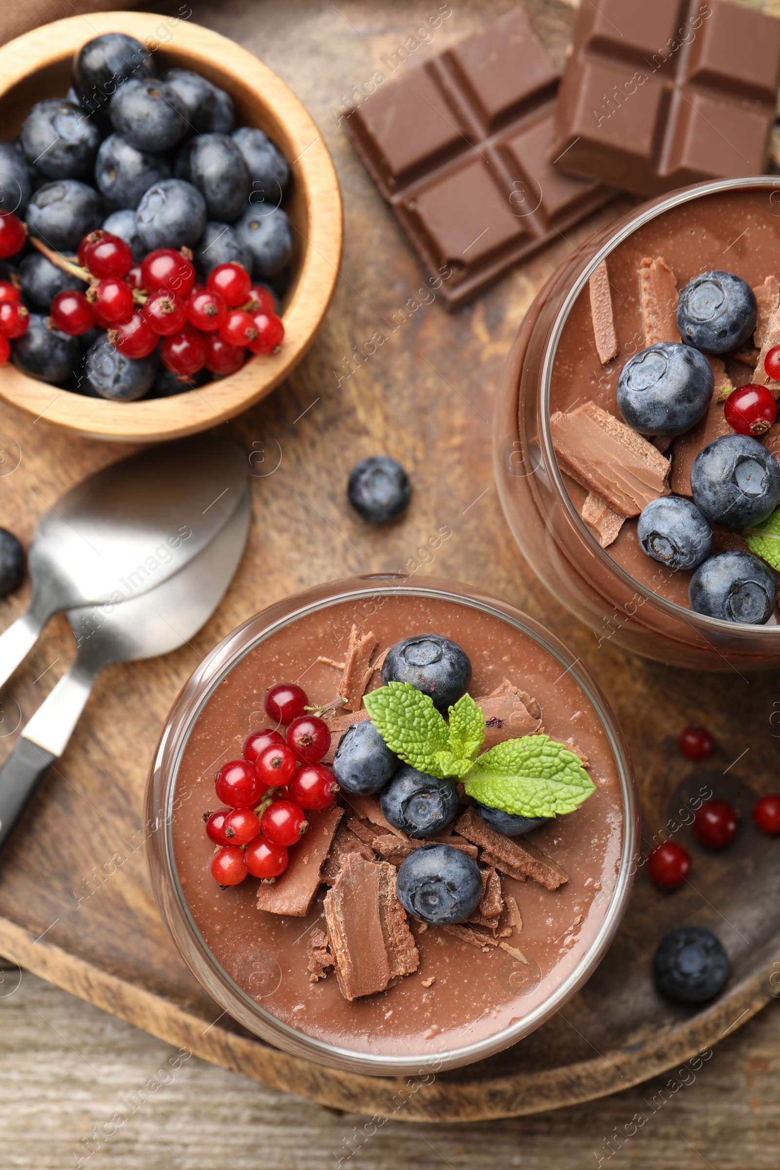 Delicious panna cotta with chocolate, berries and mint on wooden table, top view Photo of Delicious panna cotta with chocolate, berries and mint on wooden table, top view