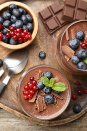 Photo of Delicious panna cotta with chocolate, berries and mint on wooden table, top view