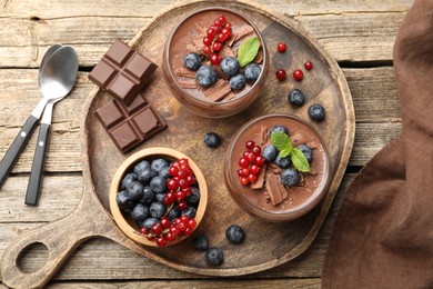 Photo of Delicious panna cotta with chocolate, berries and mint on wooden table, top view