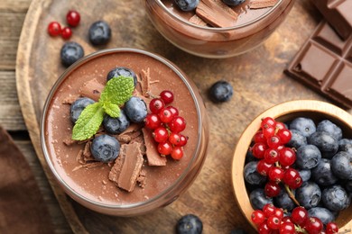 Photo of Delicious panna cotta with chocolate, berries and mint on table, flat lay
