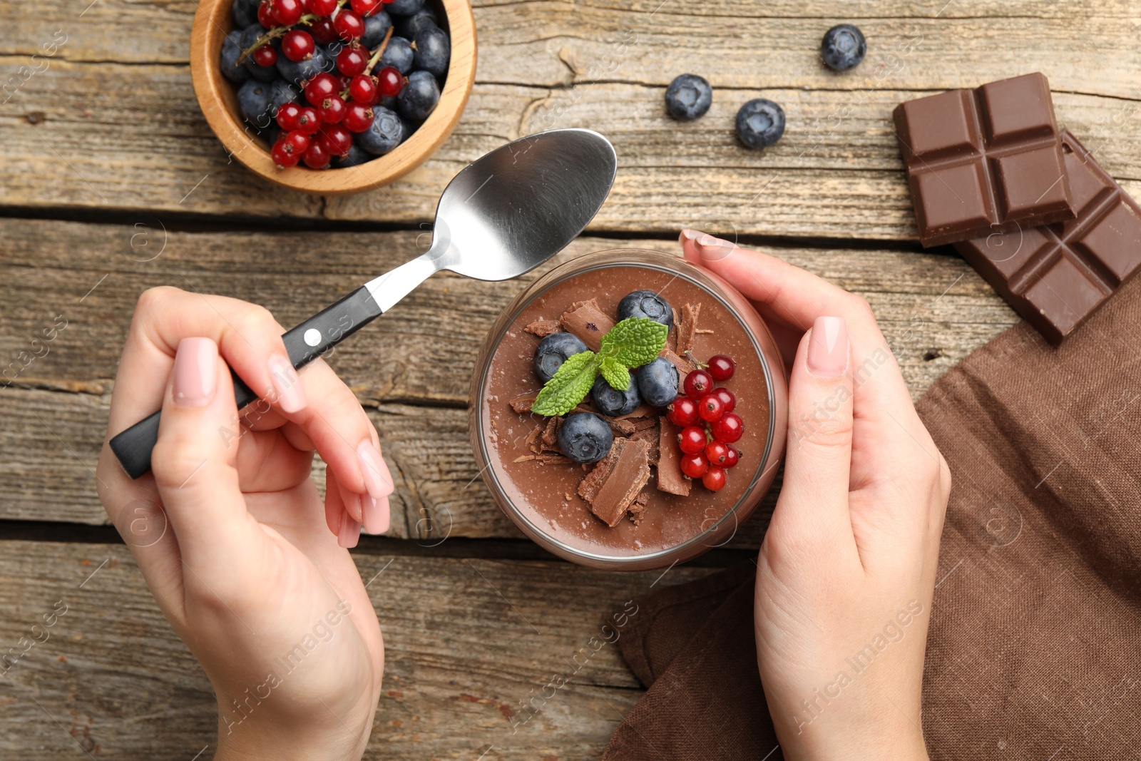 Woman with delicious chocolate panna cotta and spoon at wooden table, top view Photo of Woman with delicious chocolate panna cotta and spoon at wooden table, top view