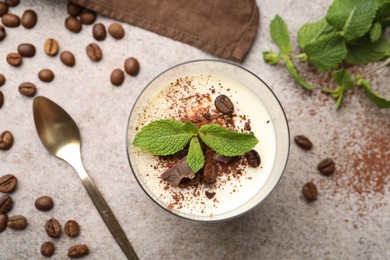 Photo of Delicious coffee panna cotta, spoon, beans and mint on grey table, flat lay