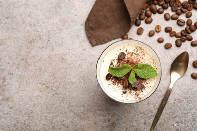 Photo of Delicious coffee panna cotta, spoon, beans and mint on grey table, flat lay. Space for text