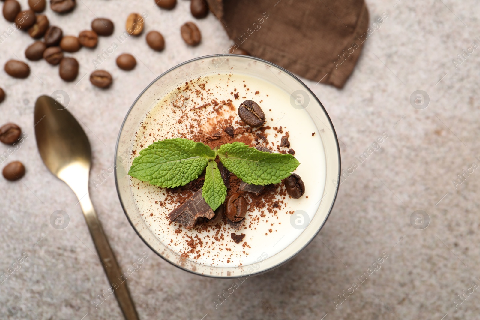 Delicious coffee panna cotta, spoon, beans and mint on grey table, flat lay Photo of Delicious coffee panna cotta, spoon, beans and mint on grey table, flat lay