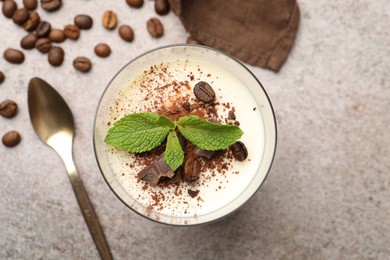 Photo of Delicious coffee panna cotta, spoon, beans and mint on grey table, flat lay