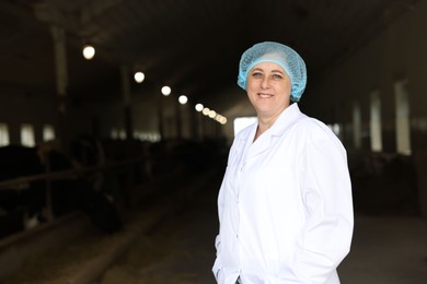 Photo of Portrait of veterinarian inside cowshed in dairy farm, space for text