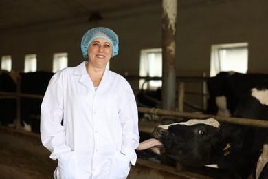 Photo of Portrait of veterinarian inside cowshed in dairy farm, space for text