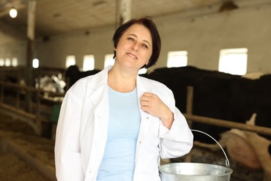Photo of Portrait of farmer with bucket near cute cows inside cowshed in dairy farm