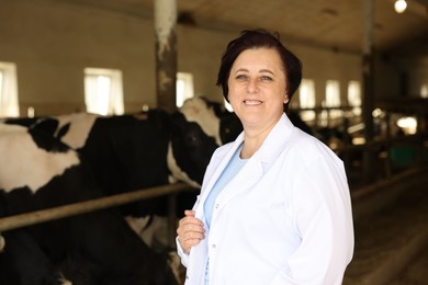 Photo of Portrait of farmer near cute cows inside cowshed in dairy farm