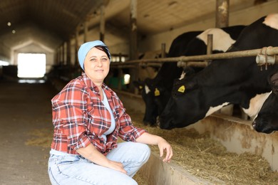 Photo of Portrait of farmer near cute cows inside cowshed in dairy farm