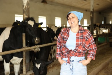 Photo of Portrait of farmer near cute cows inside cowshed in dairy farm