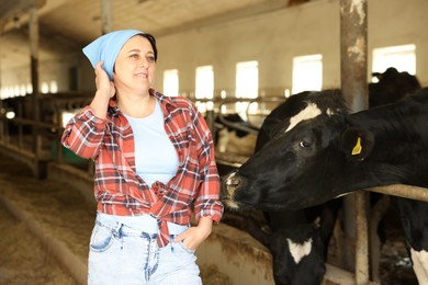 Photo of Portrait of farmer near cute cows inside cowshed in dairy farm