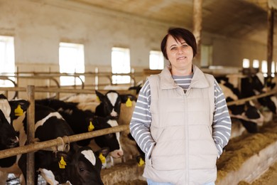 Photo of Portrait of farmer near cute cows inside cowshed in dairy farm