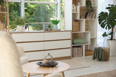 Photo of Wooden chest of drawers and other furniture in living room. Interior design