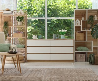 Photo of Wooden chest of drawers and other furniture in living room. Interior design