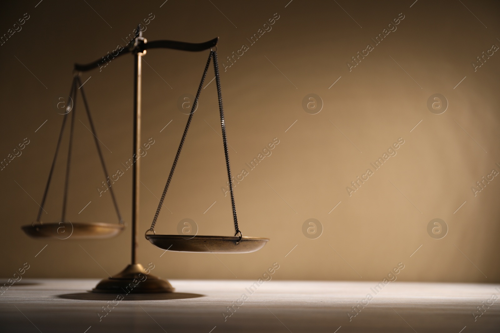 Photo of Scales of justice on table against beige background. Space for text