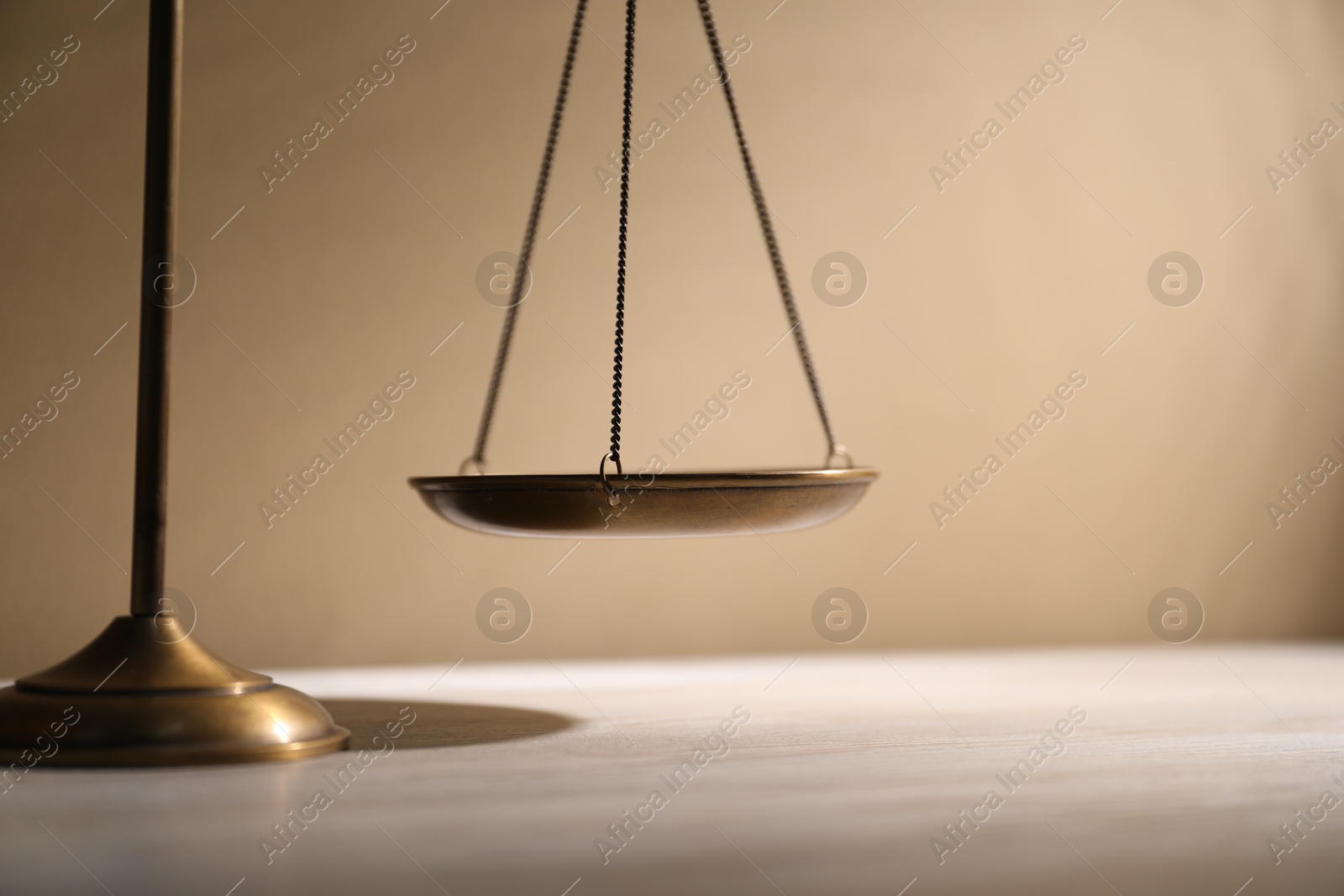 Photo of Scales of justice on table against beige background, closeup
