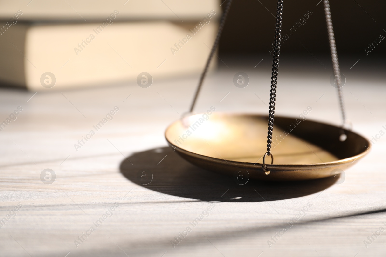 Photo of Scales of justice and books on wooden table, closeup