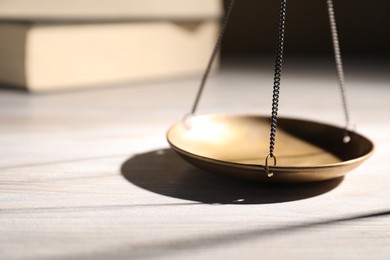 Photo of Scales of justice and books on wooden table, closeup