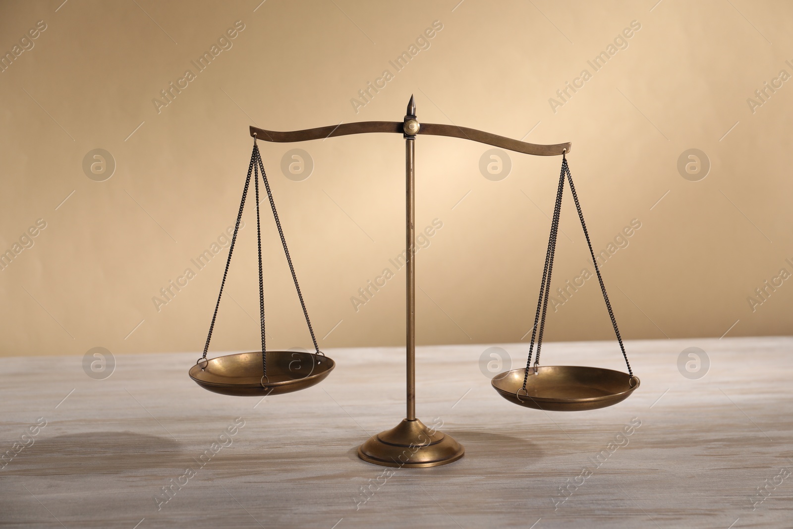 Photo of Scales of justice on table against beige background