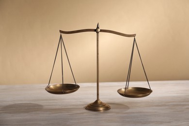 Photo of Scales of justice on table against beige background