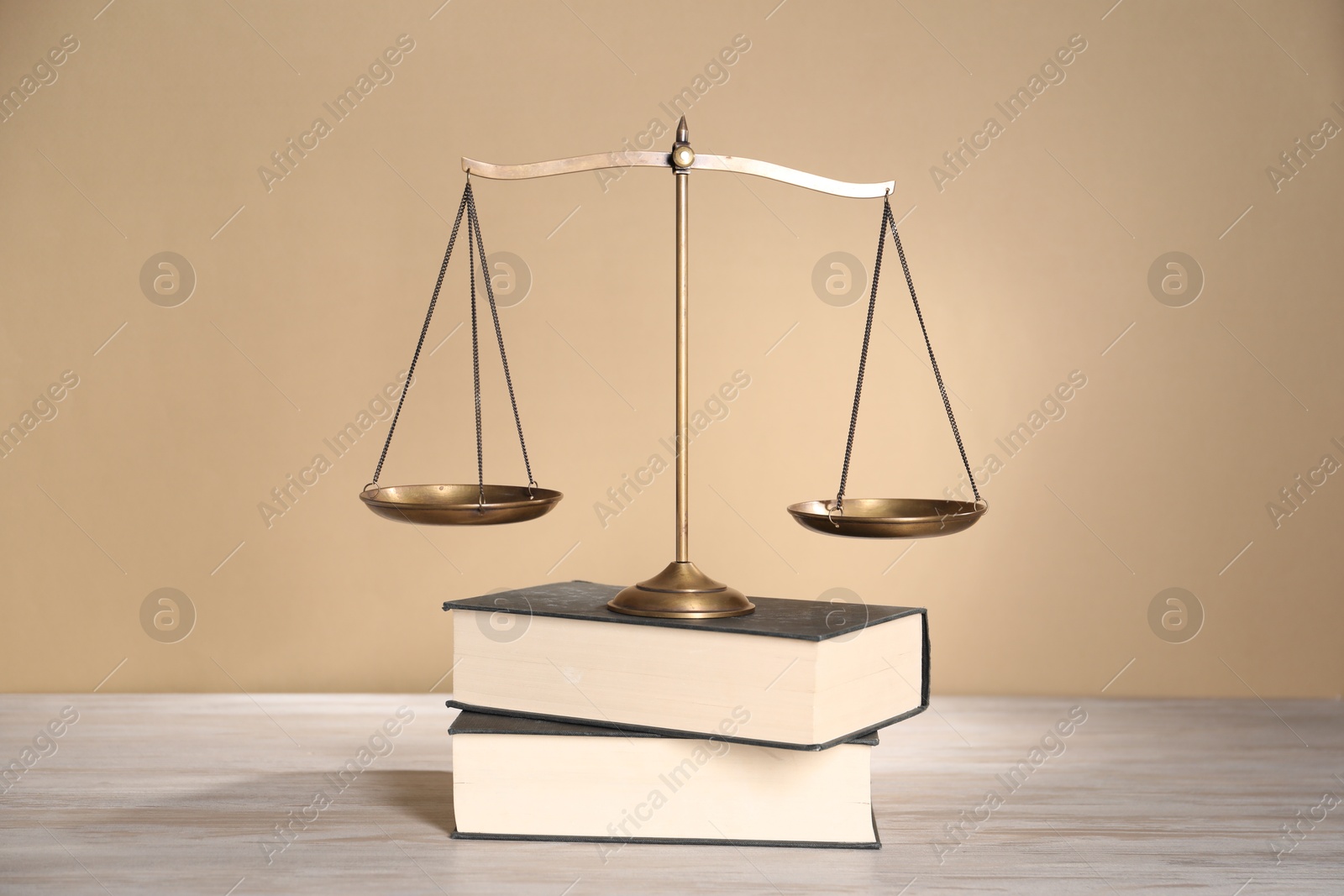 Photo of Scales of justice and books on table against beige background
