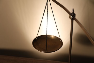 Photo of Scales of justice on beige background, closeup