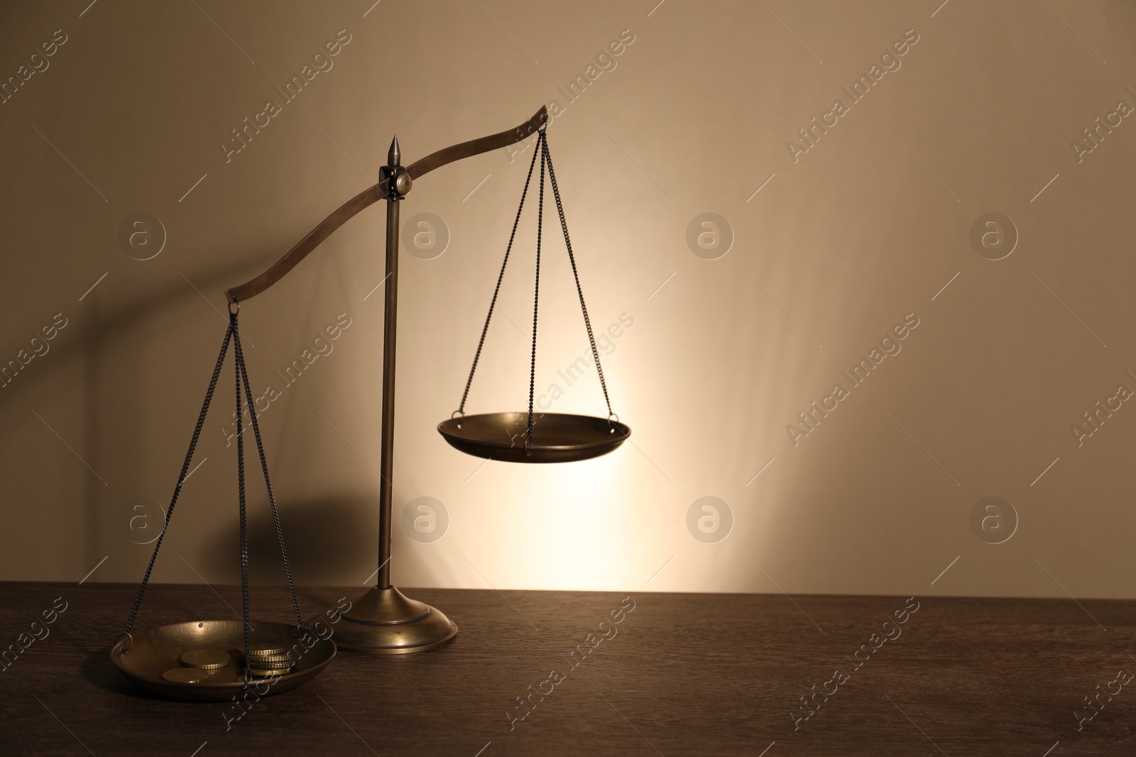Photo of Scales of justice on wooden table against beige background. Space for text