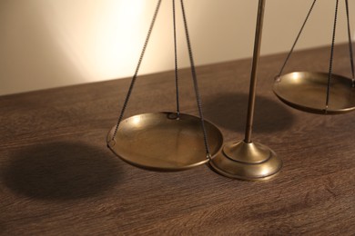 Photo of Scales of justice on wooden table, closeup