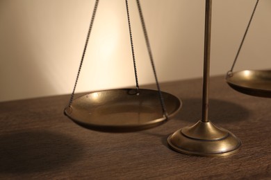 Photo of Scales of justice on wooden table, closeup