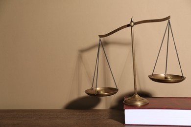 Photo of Scales of justice and book on table against beige background. Space for text