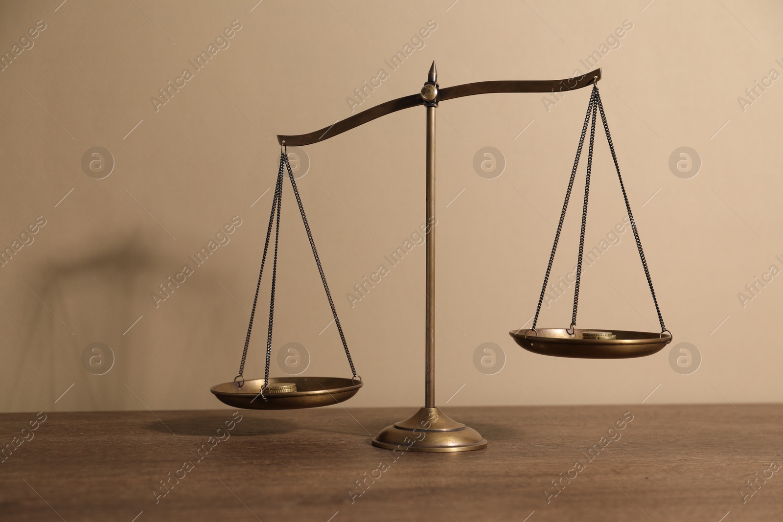 Photo of Scales of justice on wooden table against beige background