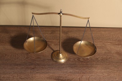 Photo of Scales of justice on wooden table, above view