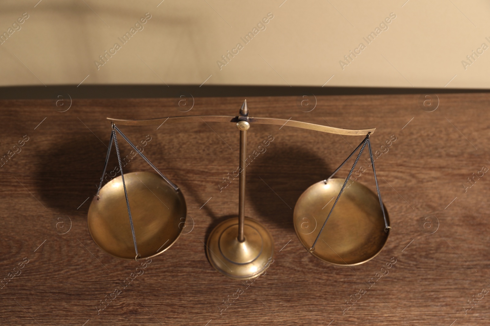 Photo of Scales of justice on wooden table, above view