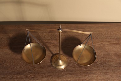 Photo of Scales of justice on wooden table, above view