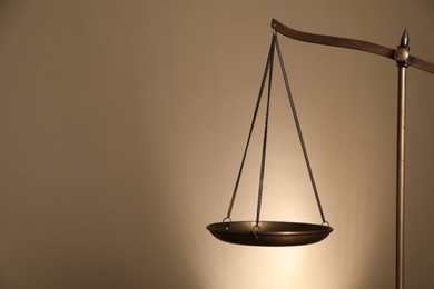 Photo of Scales of justice on beige background, closeup. Space for text