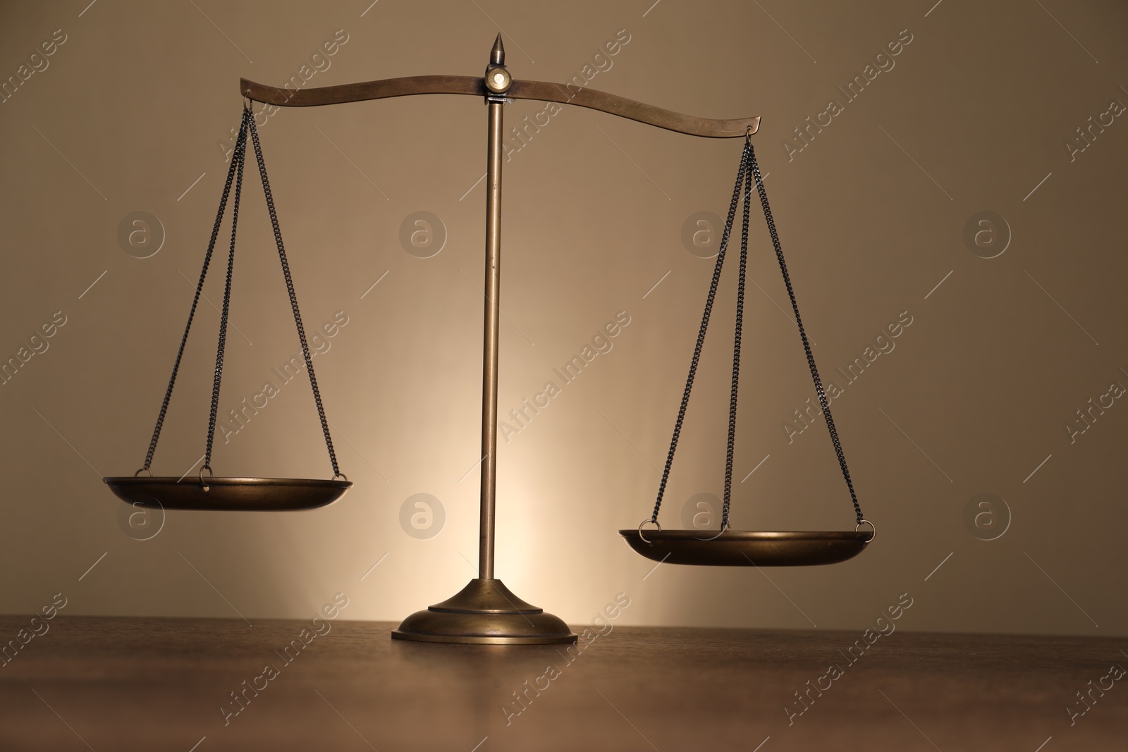 Photo of Scales of justice on wooden table against beige background